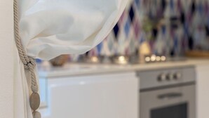 Une cuisine avec des meubles blancs, une cuisinière et un four à micro-ondes.