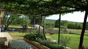 A covered patio with a table and benches, surrounded by greenery and a stone wall. - Charmantes Ferienhaus in Bartići mit Terrasse by Interhome (Drenje)