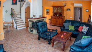 Ein geräumiges Wohnzimmer mit Kamin, Essbereich und einer Treppe, die zu einer oberen Ebene führt.