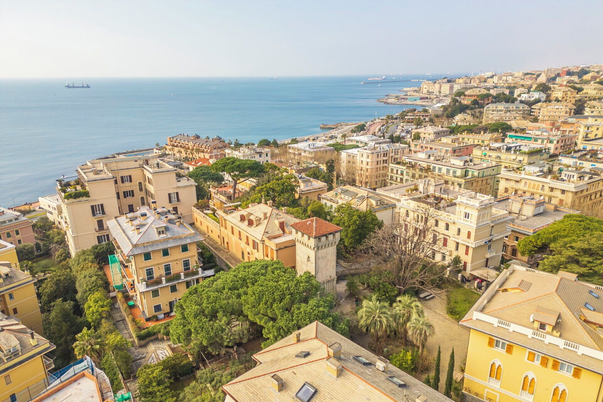 Paesaggio costiero urbano con edifici densi, una torre importante e vista sul mare.