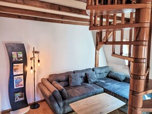 Ein gemütliches Wohnzimmer mit einer Eckcouch, einem Holztisch und einer modernen Lampenleuchte.