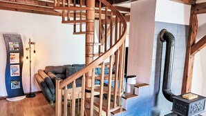 Eine hölzerne Wendeltreppe in einem Raum mit Kamin, einer Couch und einem Wanddisplay.