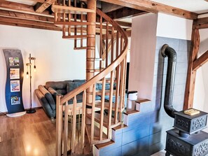 Eine hölzerne Wendeltreppe in einem Raum mit Kamin, einer Couch und einem Wanddisplay.