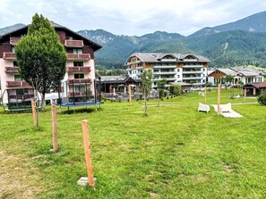 A hotel with multiple floors, outdoor seating, and a grassy area with trees. - Apartment Daniel by Interhome (Gosau)
