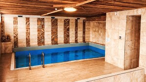 Een zwembad met houten plafond en betegelde wanden.