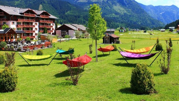 A hotel with multiple balconies, a grassy lawn, and colorful canopies. - Deluxapartment Simon by Interhome (Gosau)