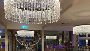 A restaurant interior with wooden flooring, round tables, and a large chandelier. - Deluxapartment Simon by Interhome (Gosau)