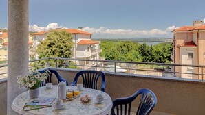 Un balcó amb una taula rodona preparada per esmorzar, amb vista a un paisatge idíl·lic d'edificis i arbres.