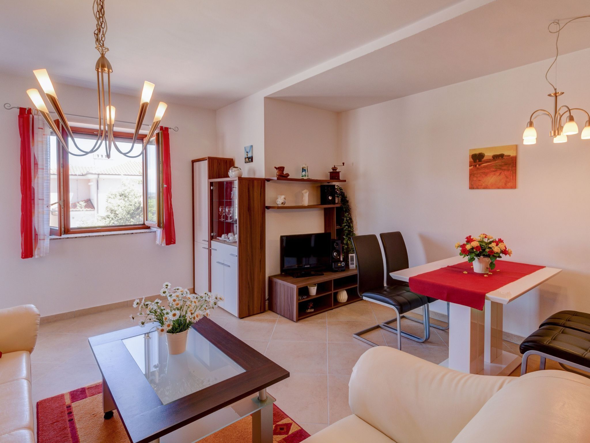 A modern living room with a glass-top coffee table, white sofas, a red dining table, and a TV stand.