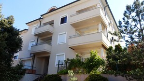 Un edifici residencial de diversos pisos amb balcons, una entrada central i vegetació als voltants.