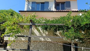 A two-story building with a stone facade and a balcony with a metal railing.