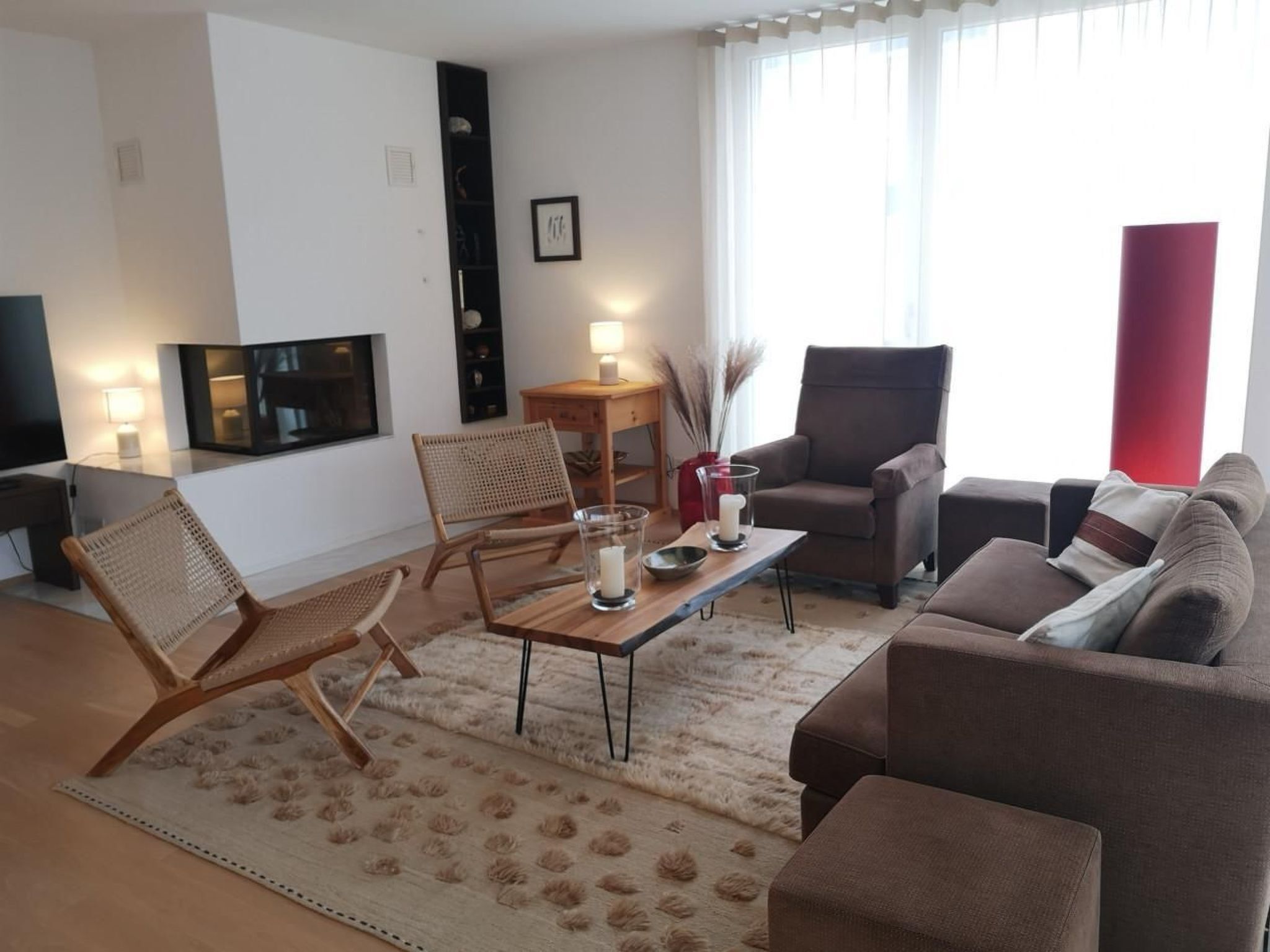 En moderne stue med sofa, to stole, sofabord og fjernsyn.