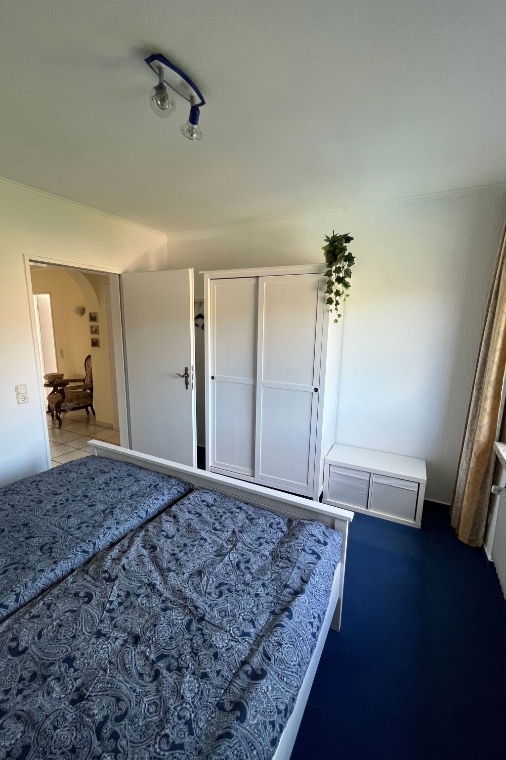 Een slaapkamer met een bed, kledingkast en plafondventilator.