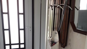 Ein Flur mit einer Holztür, einem Kleiderständer, einer kleinen Kommode mit einer Vase und einem Spiegel an der Wand.