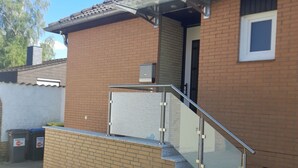 Ein zweistöckiges Haus mit Ziegelaußenwand, einem Ziegeldach und einem Glasgeländer an der Treppe.