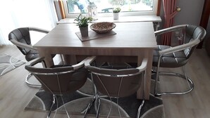 Ein Essbereich mit einem Holztisch, sechs Stühlen, einem Blumentopf und einem Laternenlichtbrett.