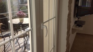 Une pièce dotée d’une grande fenêtre, d’un téléviseur fixé au mur et d’une table avec des chaises à l’extérieur.