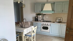 Une cuisine avec des meubles de couleur bleu clair, une cuisinière à gaz, une machine à café et une horloge au mur.