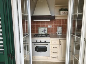 Een koelkast, een oven, een vaatwasser, kookgerei, borden en bestek