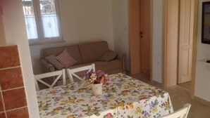 A dining area with a floral tablecloth, a sofa, and a door in the background. - Appartement in Stoja mit Möbliertem Balkon by Interhome (Pula)