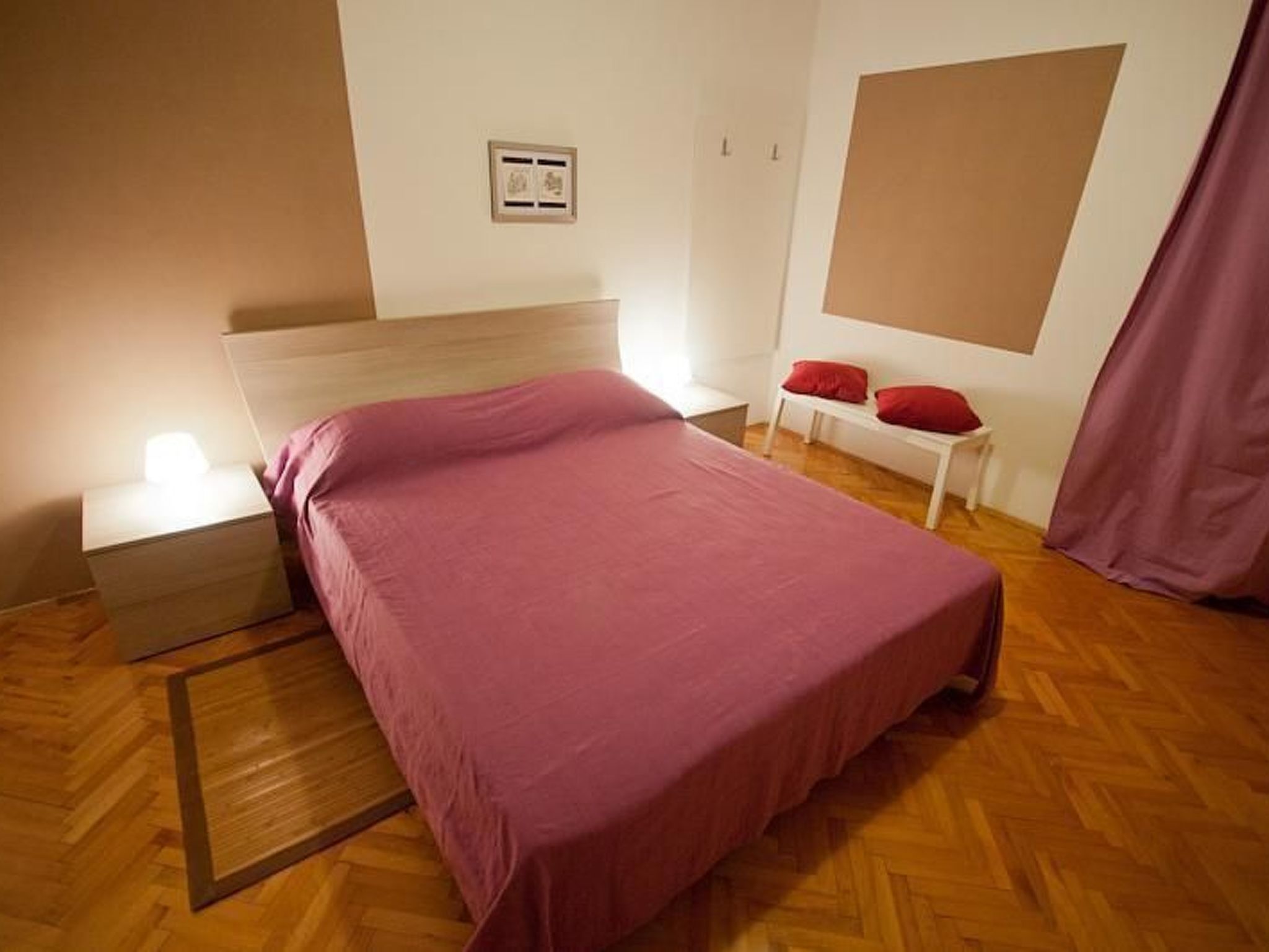 Une chambre à coucher avec un lit, une table de chevet et une bouche d’aération fixée au mur.
