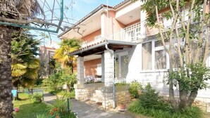 A two-story house with a covered porch, a small garden with various plants, and a concrete pathway leading to the entrance. - Wohnung 'Ivaana' mit Privatparkplatz by Interhome (Rovinj)