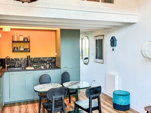 A modern kitchen with a built-in island, a dining area with a marble table, and a blue accent chair. - Apartment "Blue dream" in Strandnähe by Interhome (Carantec)
