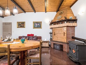 A cozy living room with a wooden ceiling, a fireplace, a dining table with chairs, and a sofa. - Haus Plum by Interhome (Drenje)