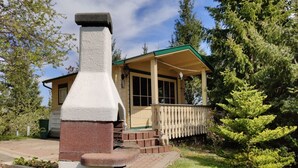 Une cabane rustique dotée d’une cheminée, d’un porche et d’une terrasse en bois.