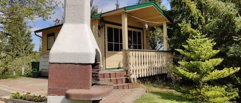 A rustic cabin with a chimney, a porch, and a wooden deck.