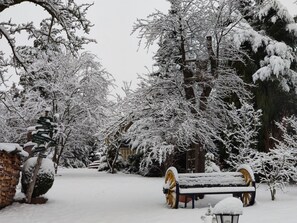 Un banco cubierto de nieve y un cartel de madera en un parque.