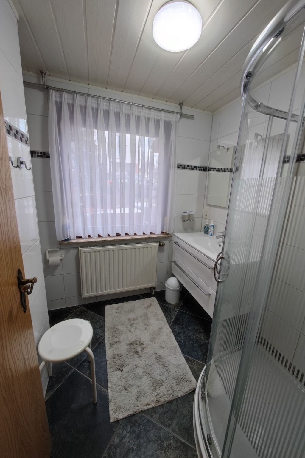 Et badeværelse med toilet, vask, brusebad og en radiator.