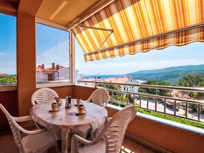 A balcony with a table set for two, overlooking a scenic landscape. - Modernes Apartment mit zwei Schlafzimmern by Interhome (Rabac)