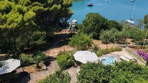 Une propriété située sur la côte, dotée d’une piscine, d’un espace extérieur aménagé et offrant une vue sur la mer et les bateaux.