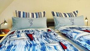 Ett hotellrum med två sängar, randiga kuddar och en tavla som föreställer en solnedgång över en brygga.