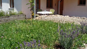 A covered outdoor seating area with a table and chairs, surrounded by a garden with various plants and flowers. - am Waldrand, ideal für Bergsport by Interhome (Oberstaufen)