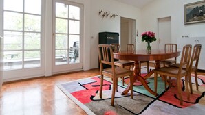 En matplats med ett runt bord, stolar, en vas med blommor och en färgglad matta.