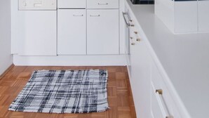Ett modernt kök med vita skåp, ett blått och vitt stänkskydd och ett trägolv.
