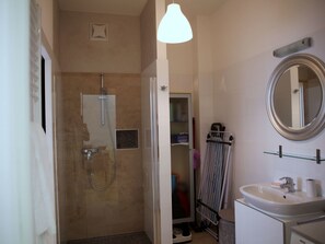 A bathroom with a shower, a sink, a mirror, and a towel rack. - Moderne Stadtwohnung by Interhome (Vienna)