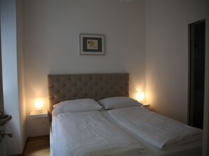 A bedroom with a tufted headboard, two bedside lamps, and a framed picture on the wall. - Moderne Stadtwohnung by Interhome (Vienna)
