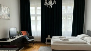 Ett modernt hotellrum med en stor säng, ett skrivbord med en dator, en stol och ett litet bord.
