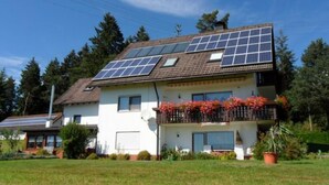 A two-story house with solar panels on the roof and a balcony with flowers. - Apartment Gaby by Interhome (Bonndorf)