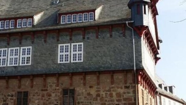 Un edificio histórico con fachada de piedra, múltiples ventanas y una torre destacada.
