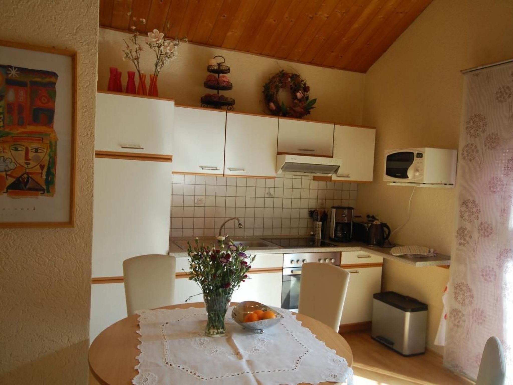 A kitchen with white cabinets, a tiled backsplash, a microwave, and a coffee maker.