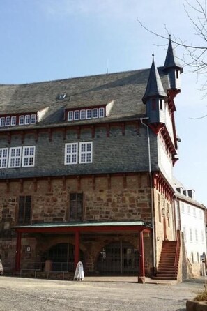 Ein historisches Gebäude mit einem steil aufragenden Dach, zahlreichen Fenstern und einem markanten Turm mit einer Turmspitze.