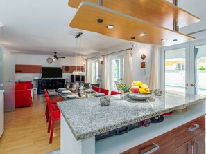 A modern kitchen with a granite countertop, red chairs, and a dining area with a table set for four. - Appartement Dino by Interhome (Buje)