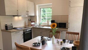 Cozinha moderna com mesa de jantar posta para quatro pessoas, forno embutido e janela com vista para o verde.