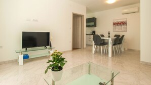 Una sala de estar moderna con televisor de pantalla plana, una mesa de centro de cristal y una planta en maceta.