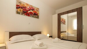 Una habitación de hotel con una cama grande, una mesita de noche, un espejo y un cuadro de flores en la pared.