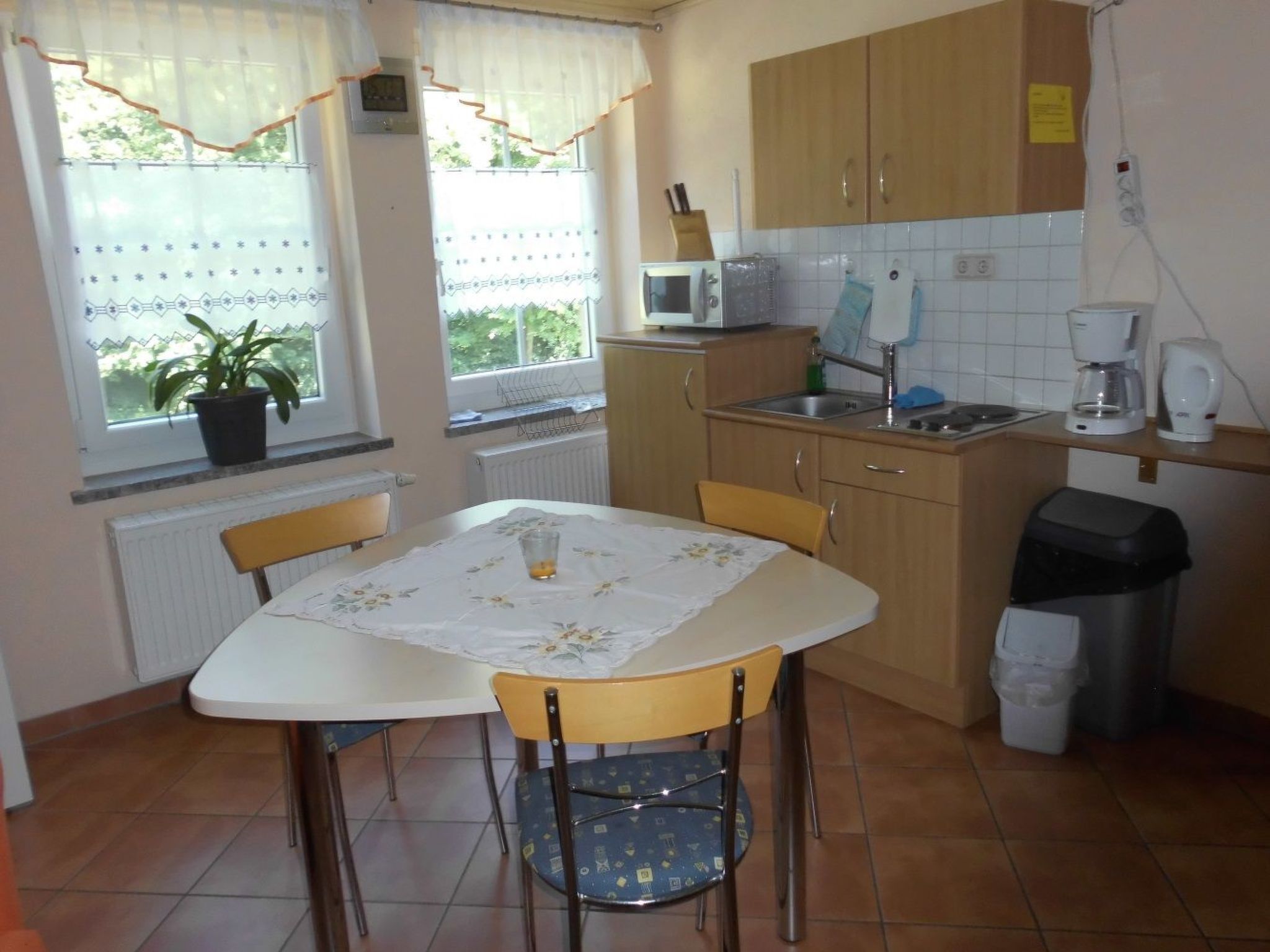 A small kitchen with a dining table, chairs, a microwave, a sink, and a coffee maker.